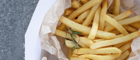 Pommes Frites mit einem Rosmarinzweig auf einer strukturierten Oberfläche.