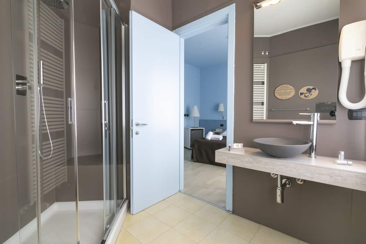 A modern bathroom with a glass-enclosed shower, a large mirror, and a sink with a vessel basin.