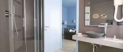 Un baño moderno con ducha de vidrio, un espejo grande y un lavabo con una pila.