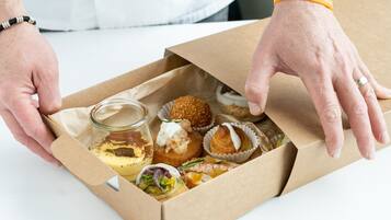 Een doos met verschillende gebakjes en een klein potje saus.