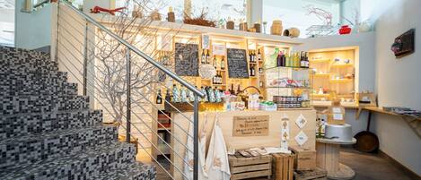 A cozy, well-lit store with a staircase leading to a second floor, wooden crates, and shelves stocked with various products.