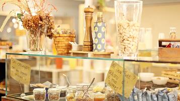 A display case with various food items and containers, including jars of nuts and seeds, a basket of dried flowers, and a pepper grinder.