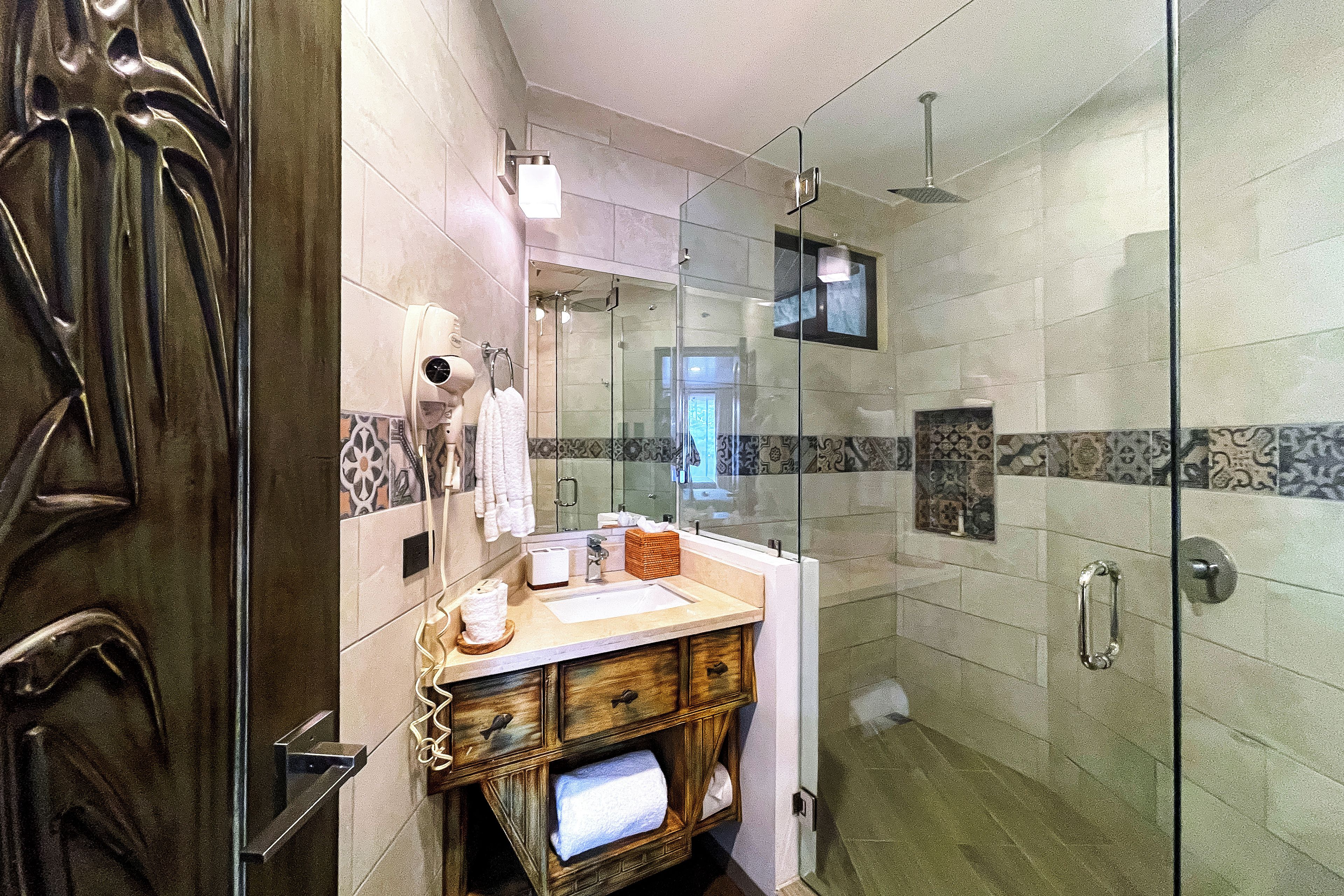 A modern bathroom with a glass shower enclosure, a wooden vanity, and a large mirror.