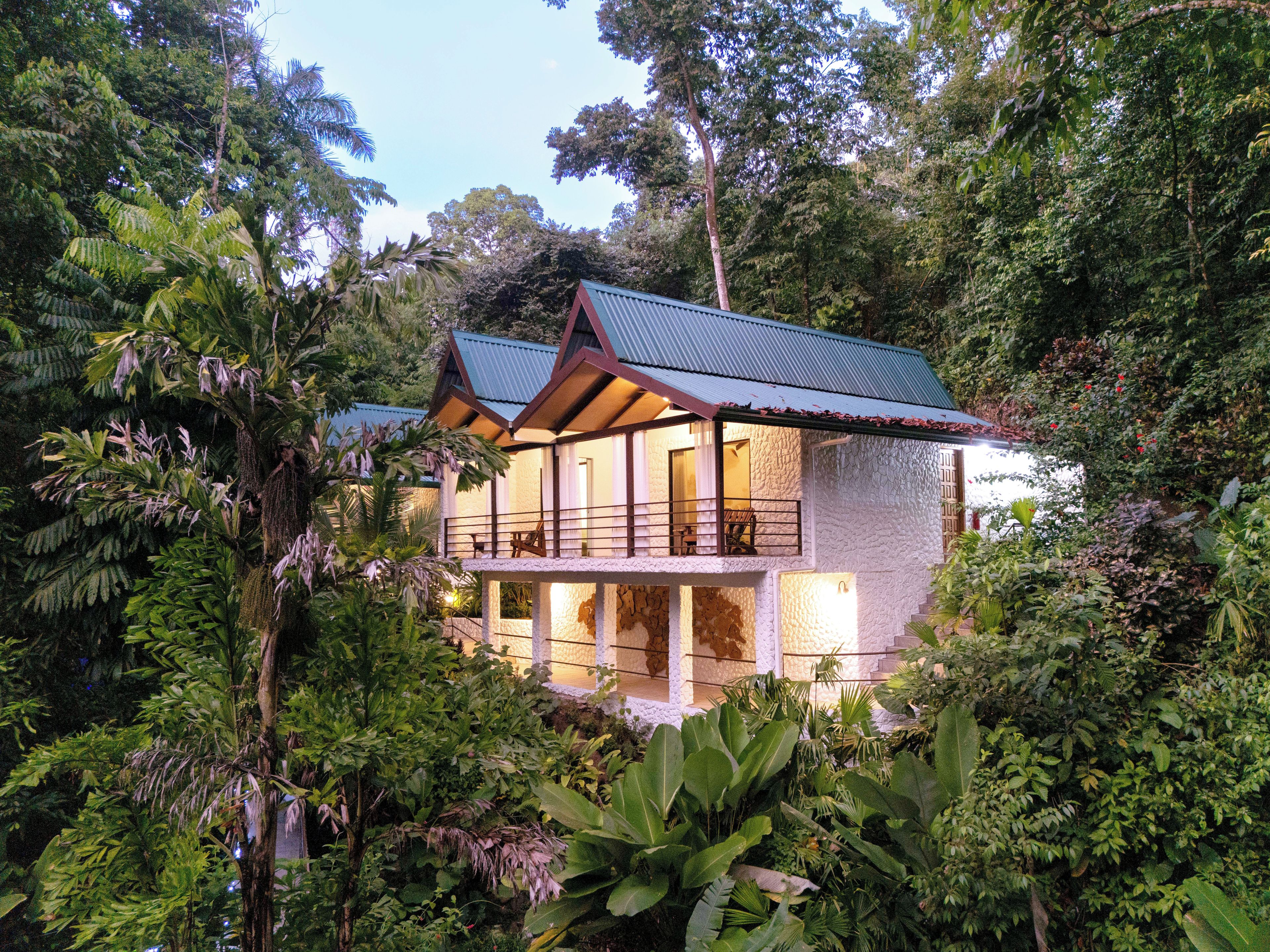 Una casa de dos pisos rodeada de densa vegetación tropical.
