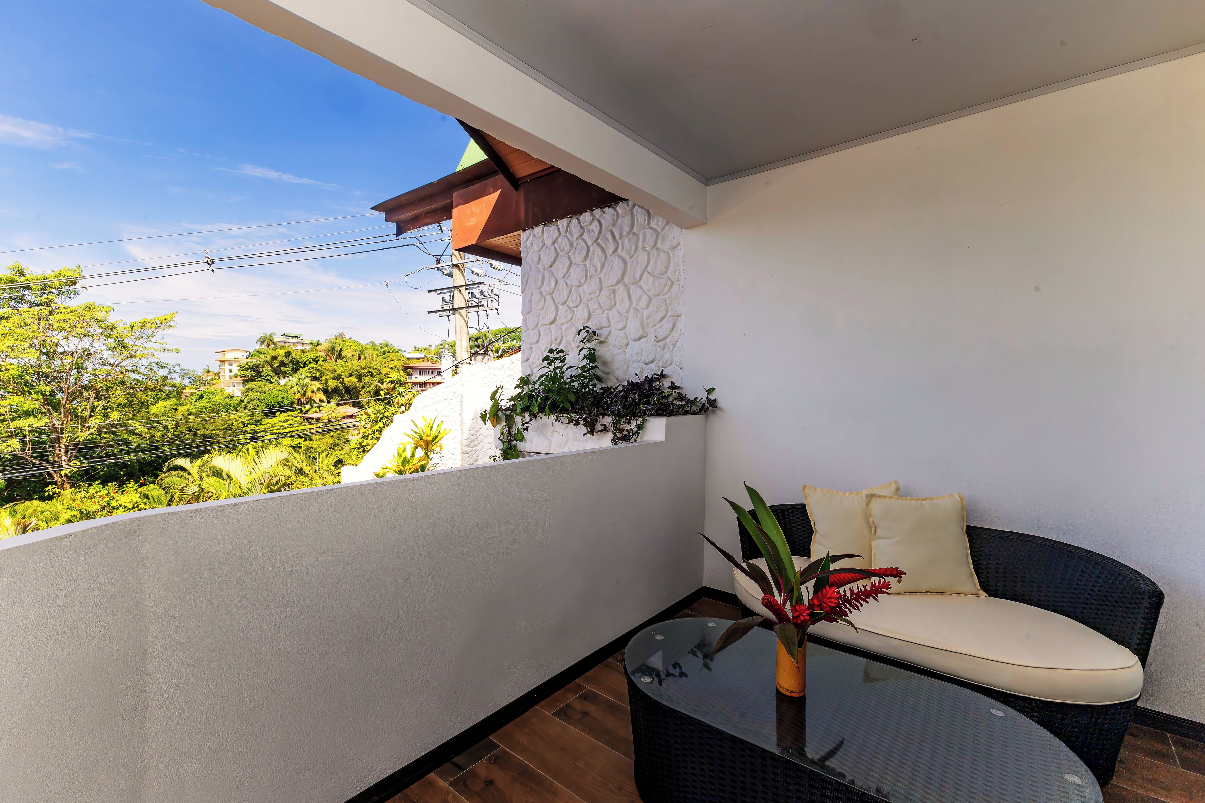 A balcony with a glass table, a cushioned chair, and a potted plant.