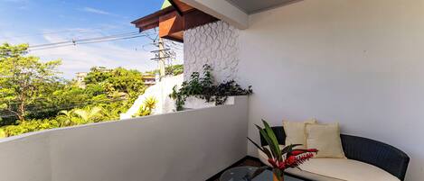 A balcony with a glass table, a cushioned chair, and a potted plant.