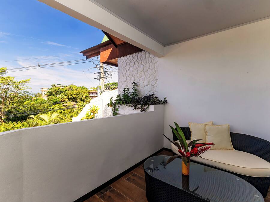 A balcony with a glass table, a cushioned chair, and a potted plant.