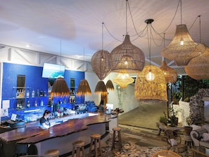 A bar area with a blue tiled backsplash, hanging rattan chandeliers, and a bar counter with stools. - ECOTICA Boutique Hotel & Spa. (Quepos)