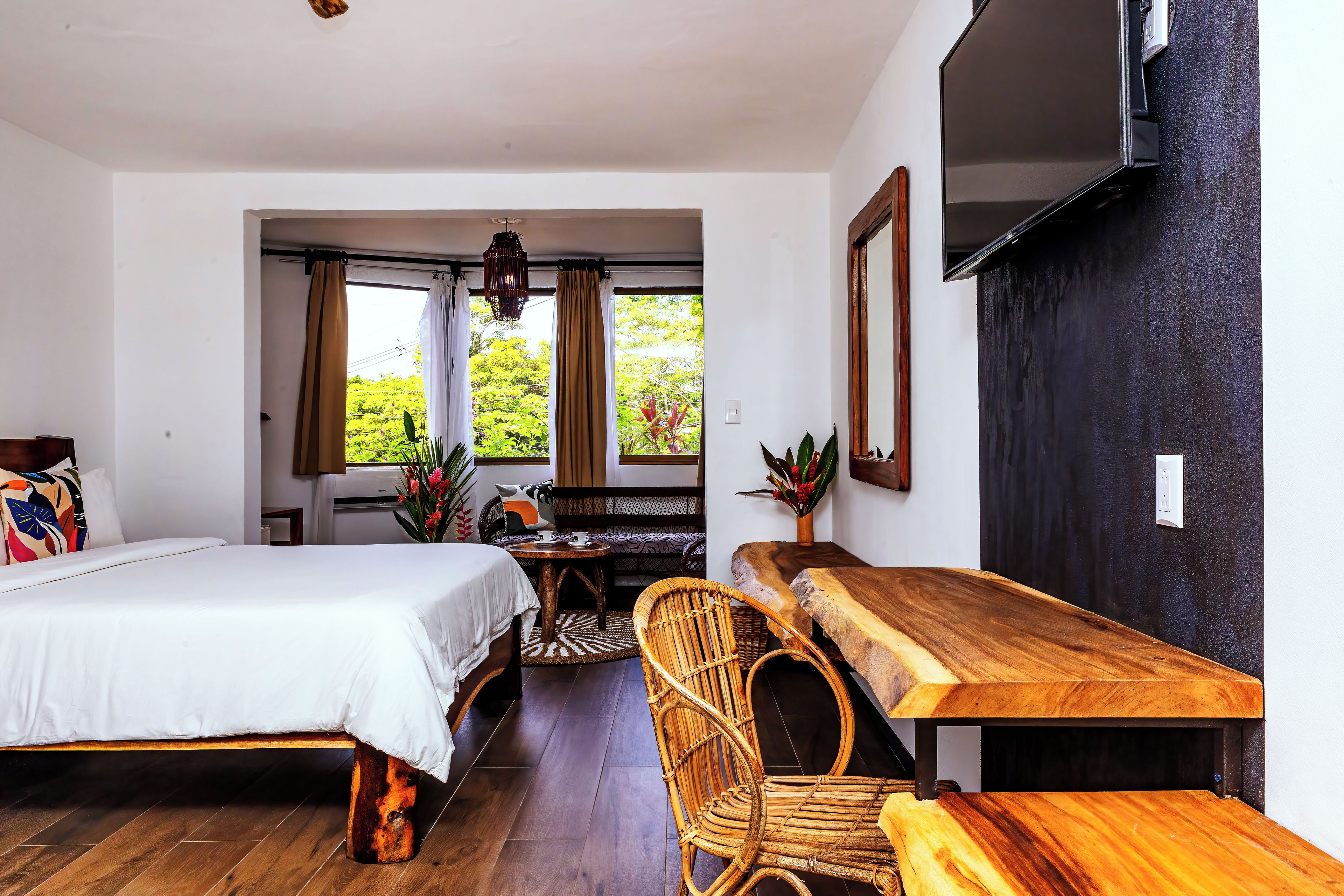 Una habitación con cama, una mesa, una silla y televisión montada en la pared.