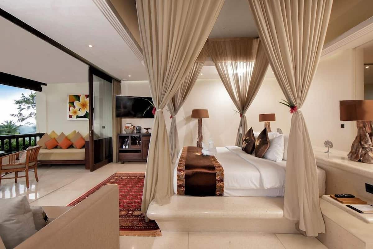Een slaapkamer met een bed, gordijnen, een televisie, een bank en een eethoek.