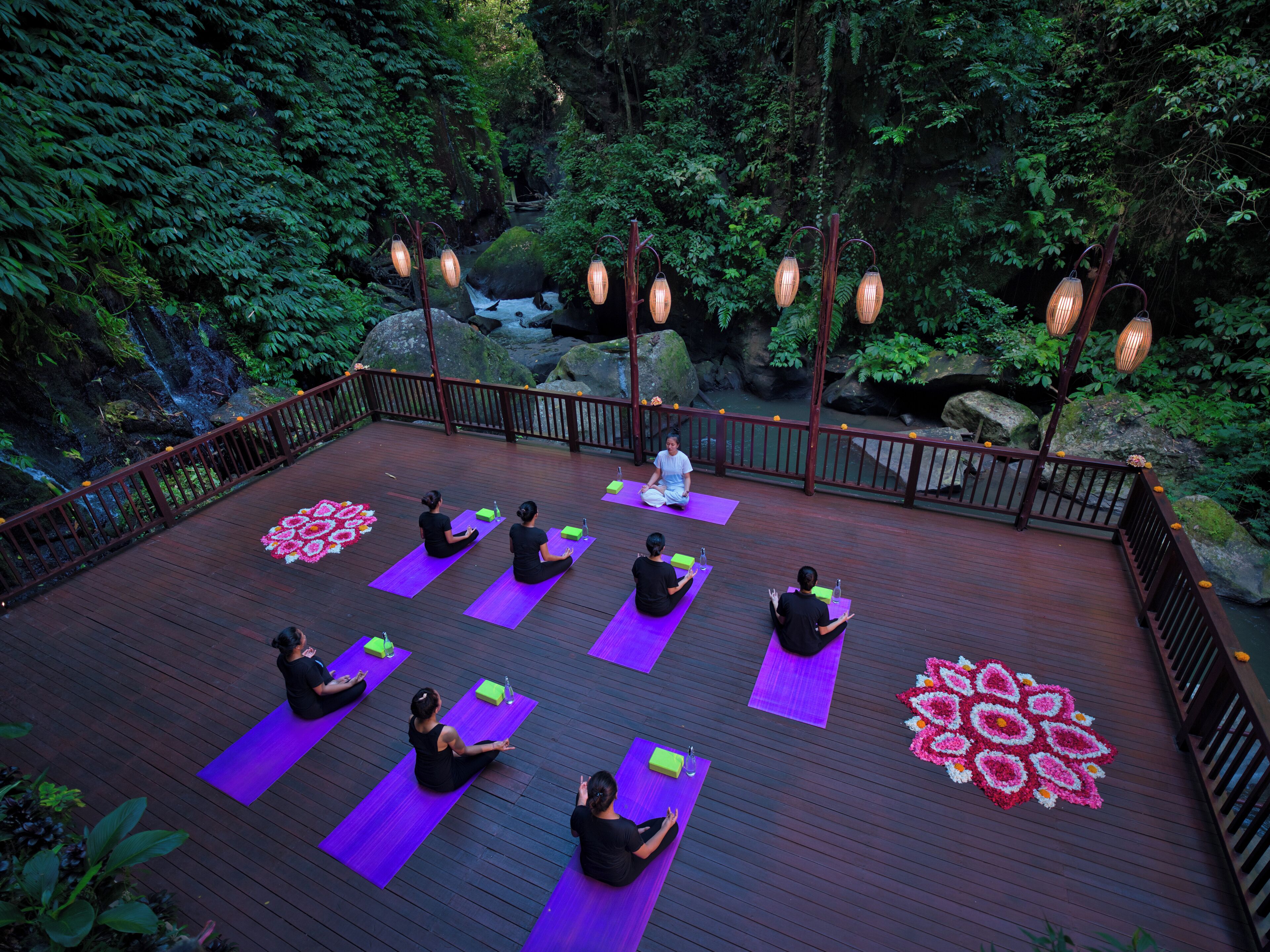 A deck with yoga mats and a mandala design, surrounded by a wooden railing and hanging lanterns.