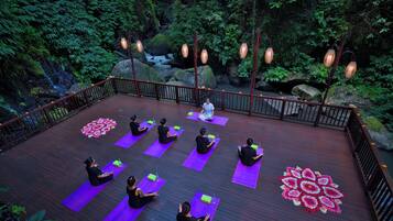A deck with yoga mats and a mandala design, surrounded by a wooden railing and hanging lanterns.