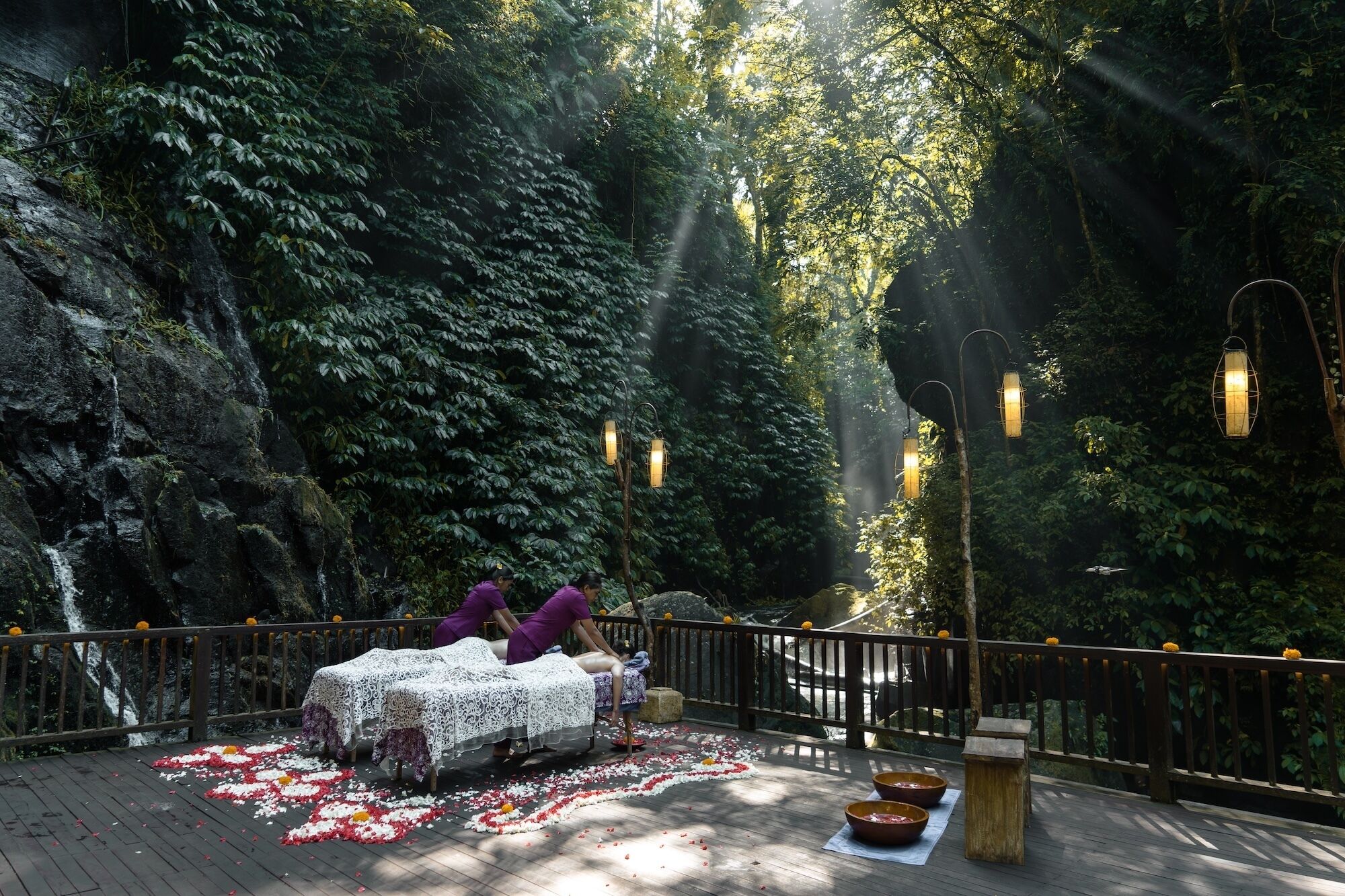A serene outdoor setting with a wooden deck, tables with lace tablecloths, and lanterns.
