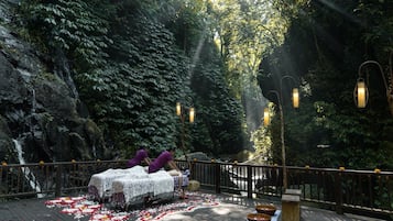 A serene outdoor setting with a wooden deck, tables with lace tablecloths, and lanterns.