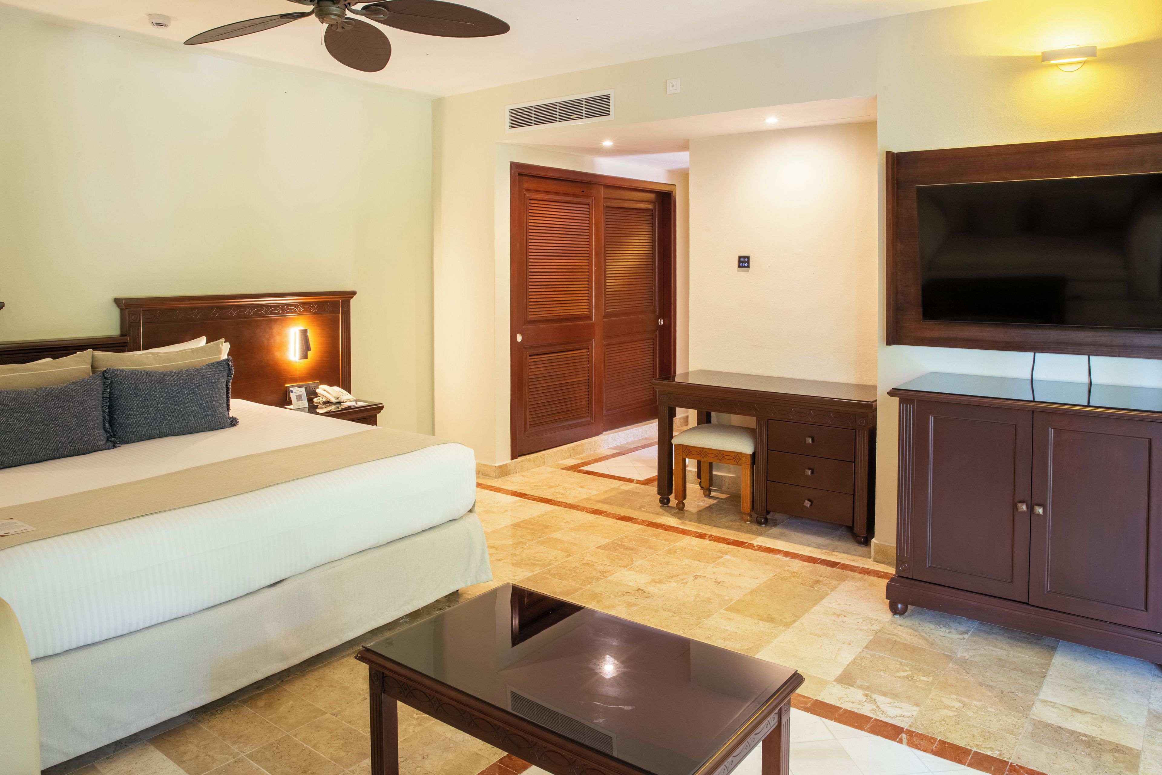 A hotel room with a bed, a desk, a television, and a wardrobe.