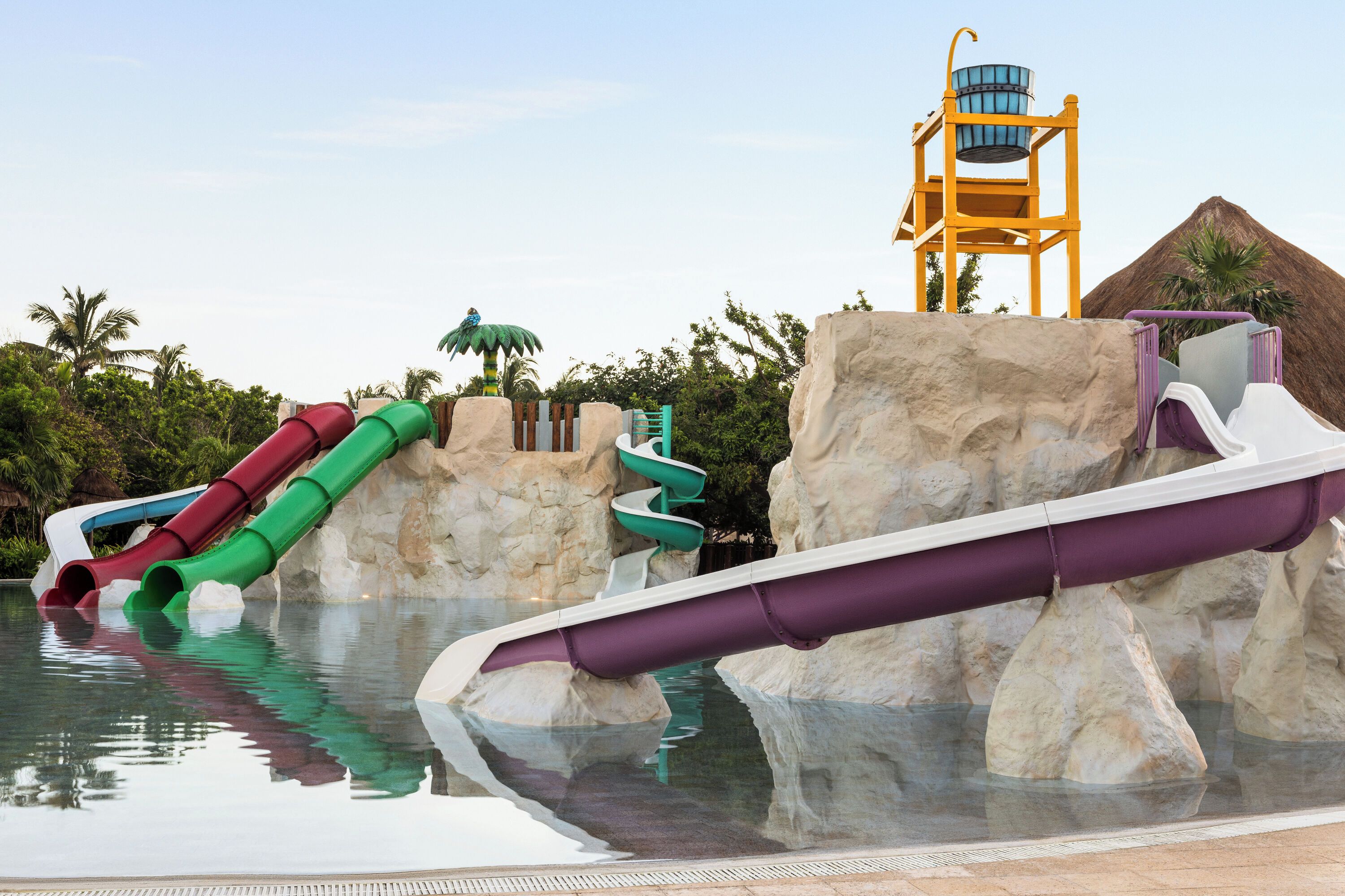 Ein Wasserpark mit mehreren Wasserrutschen, einem Rettungsschwimmturm und einer pyramidenförmigen Struktur.