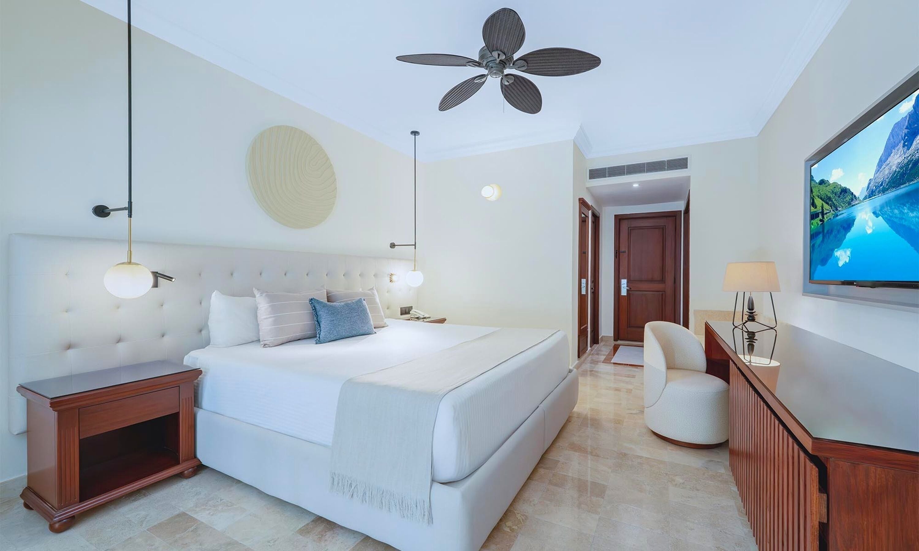 Ein modernes Hotelzimmer mit einem großen Bett, einem Deckenventilator, einem Fernseher und einem Holzkasten.