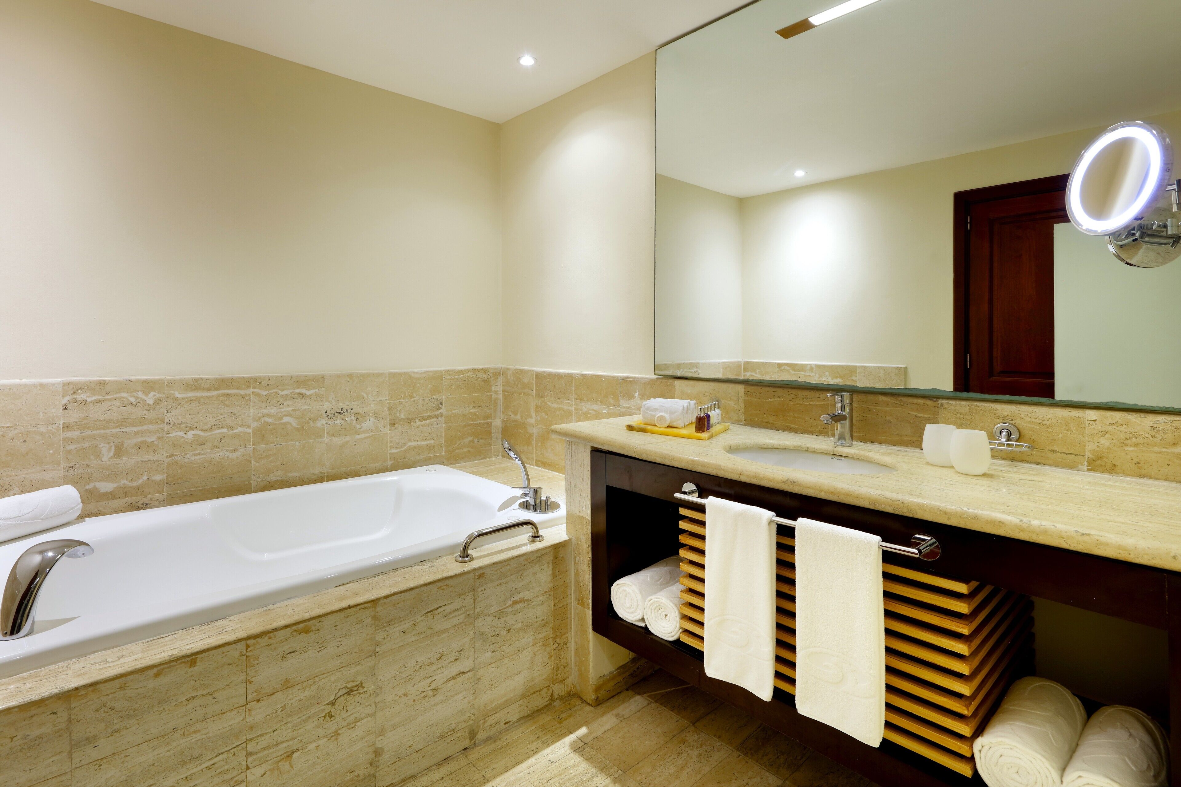 A bathroom with a bathtub, a sink, a vanity with a mirror, and towels.