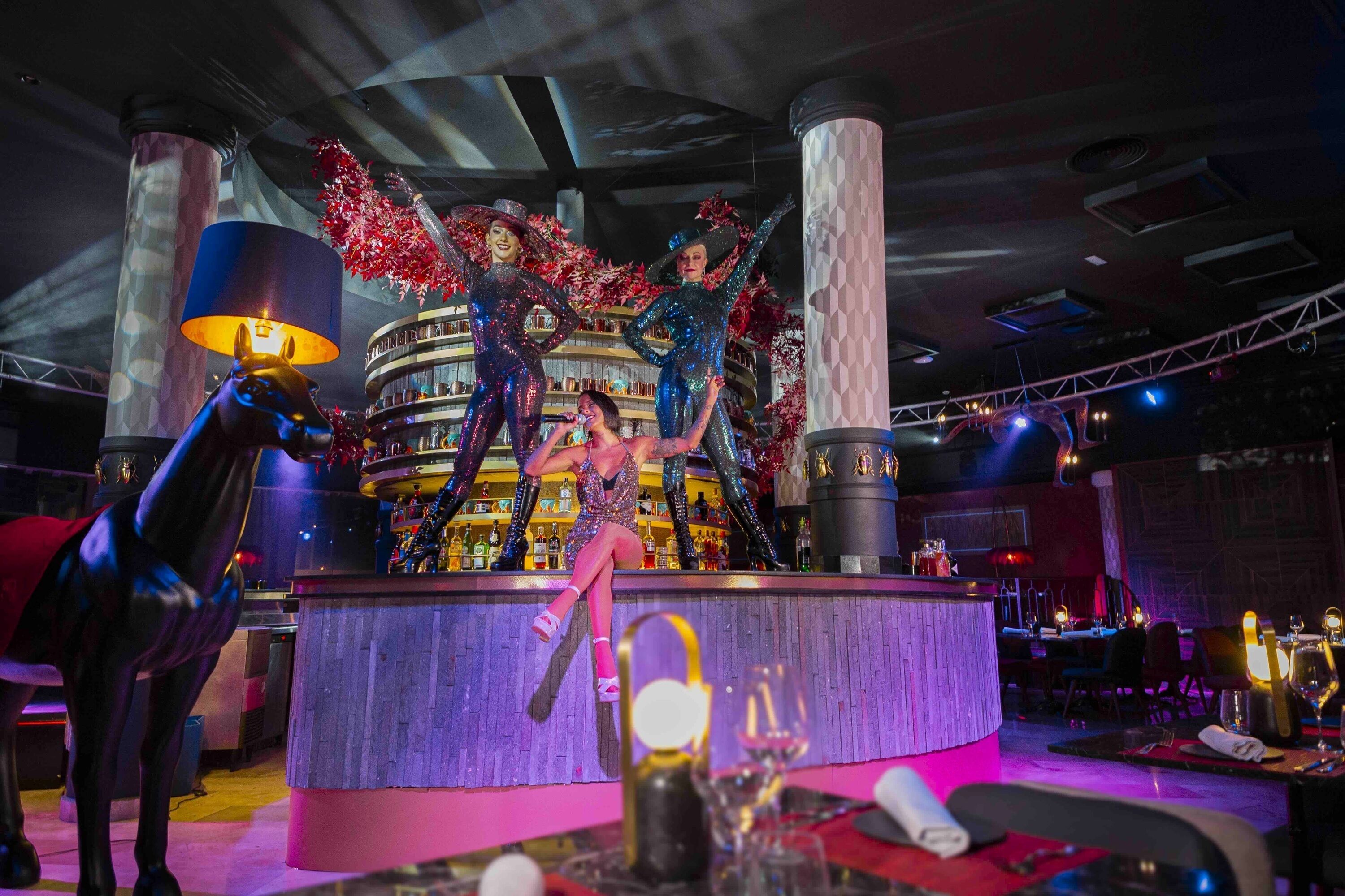 Un espace bar doté d’un comptoir circulaire, d’éléments décoratifs et d’une statue de cheval.