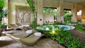 A pool area with lounge chairs, a stone wall with carvings, and lush greenery. - Grand Palladium Select White Sand Resort & Spa - All Inclusive (Kantenah)