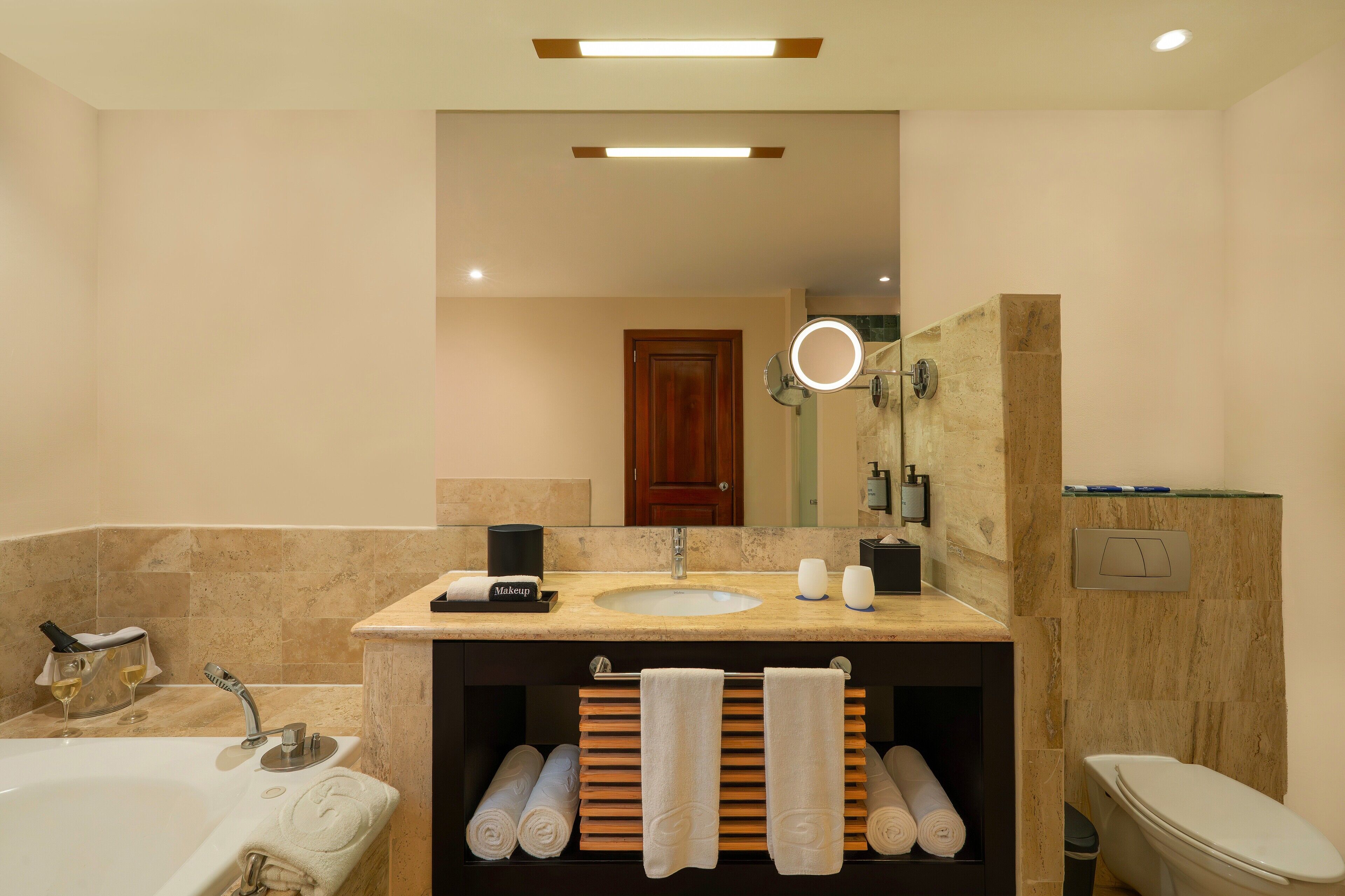 Un baño moderno con una bañera, un lavabo y un inodoro. Hay toallas y artículos de aseo en el mostrador.