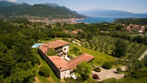 Vista aérea de una villa con piscina, rodeada de exuberante vegetación y montañas al fondo.