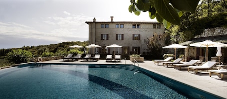 Una piscina al aire libre, sombrillas, sillones reclinables de piscina