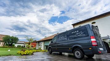 A black van parked in a driveway with a clear sky and clouds.