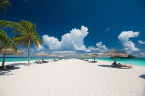 On the beach, white sand, sun loungers, beach towels