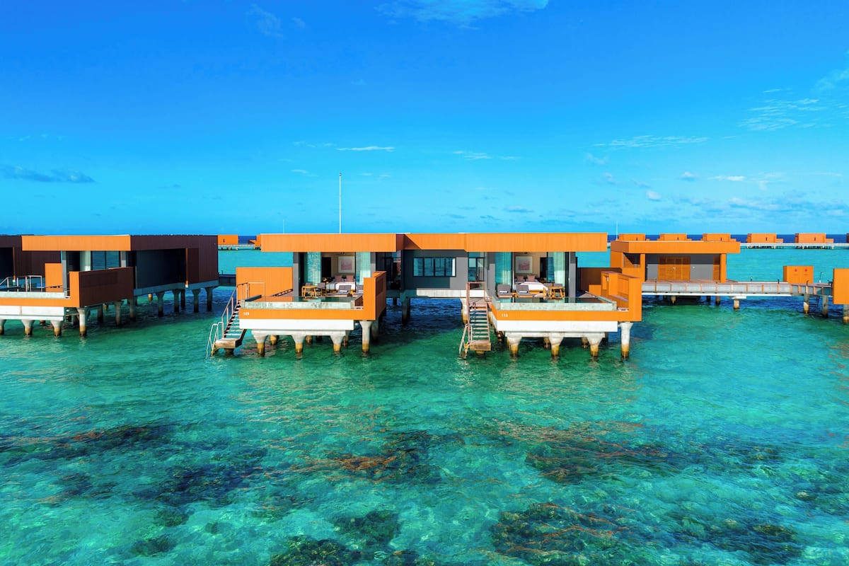 Bungalows sobre el agua con aguas cristalinas y un cielo brillante.