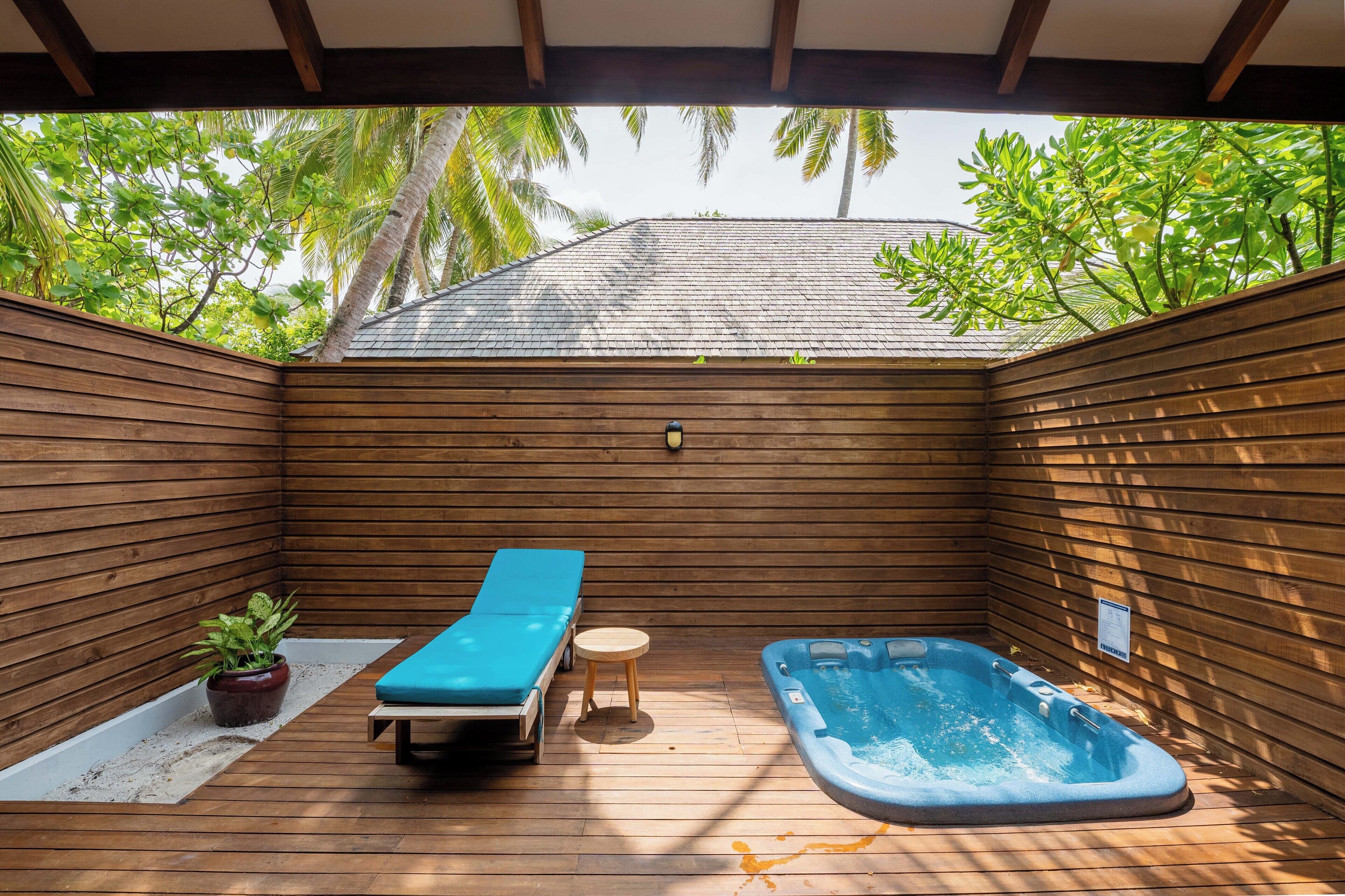 A wooden deck with a hot tub, a lounge chair, and a small table.