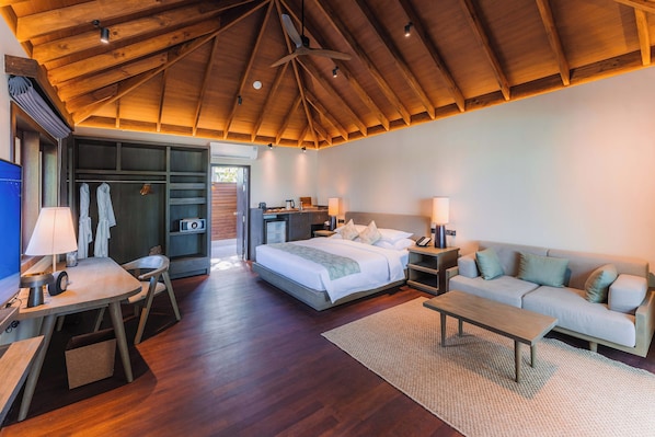 Habitación de hotel moderna con techo de madera, cama, sofá, escritorio y vestidor.
