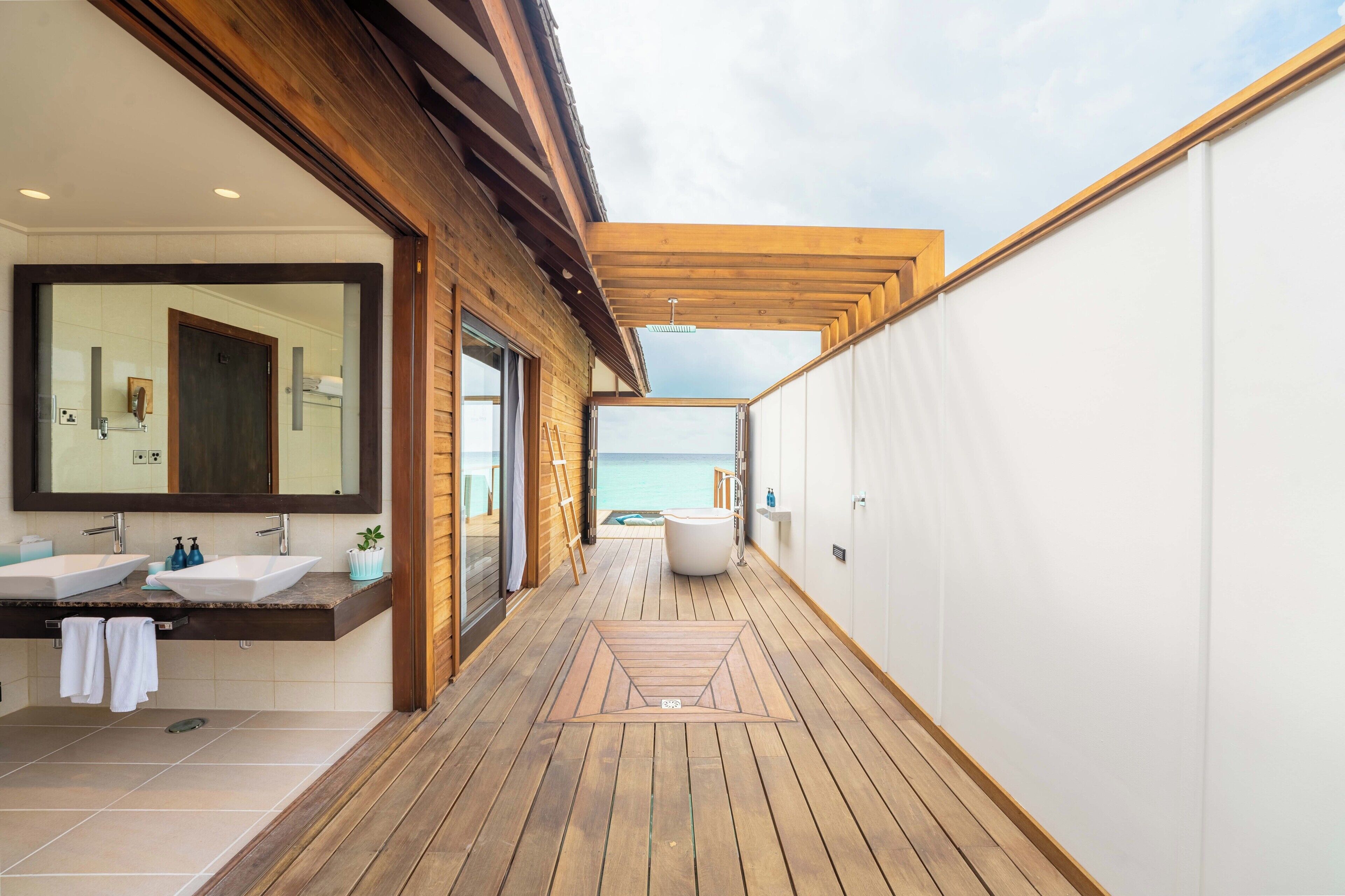 A modern bathroom with two sinks, a large mirror, and a bathtub.