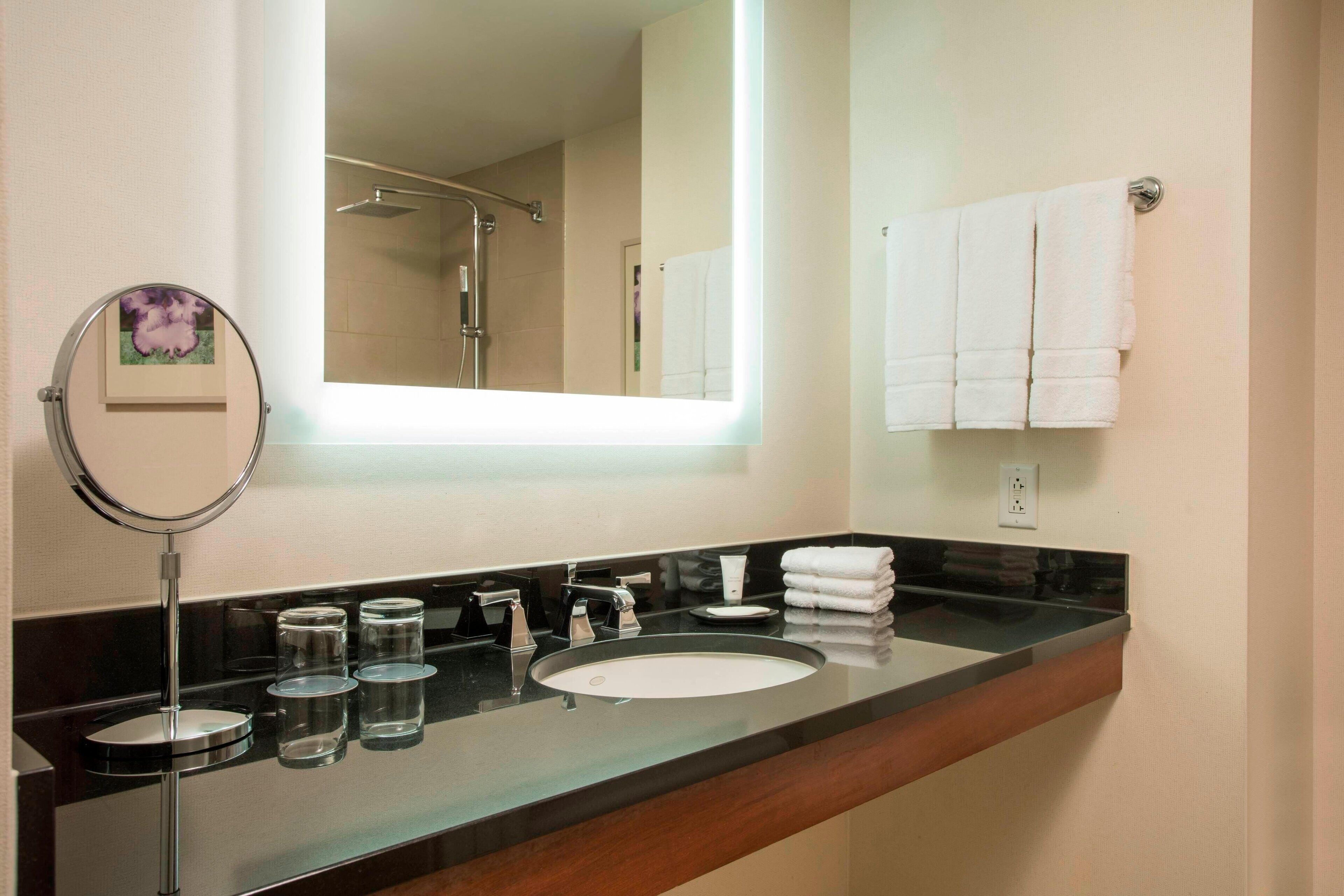 A modern bathroom with a large mirror, a sink, and a towel rack.