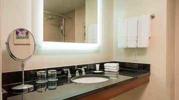 A modern bathroom with a large mirror, a sink, and a towel rack.