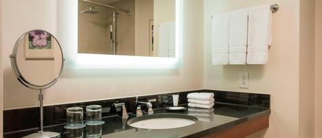 A modern bathroom with a large mirror, a sink, and a towel rack.