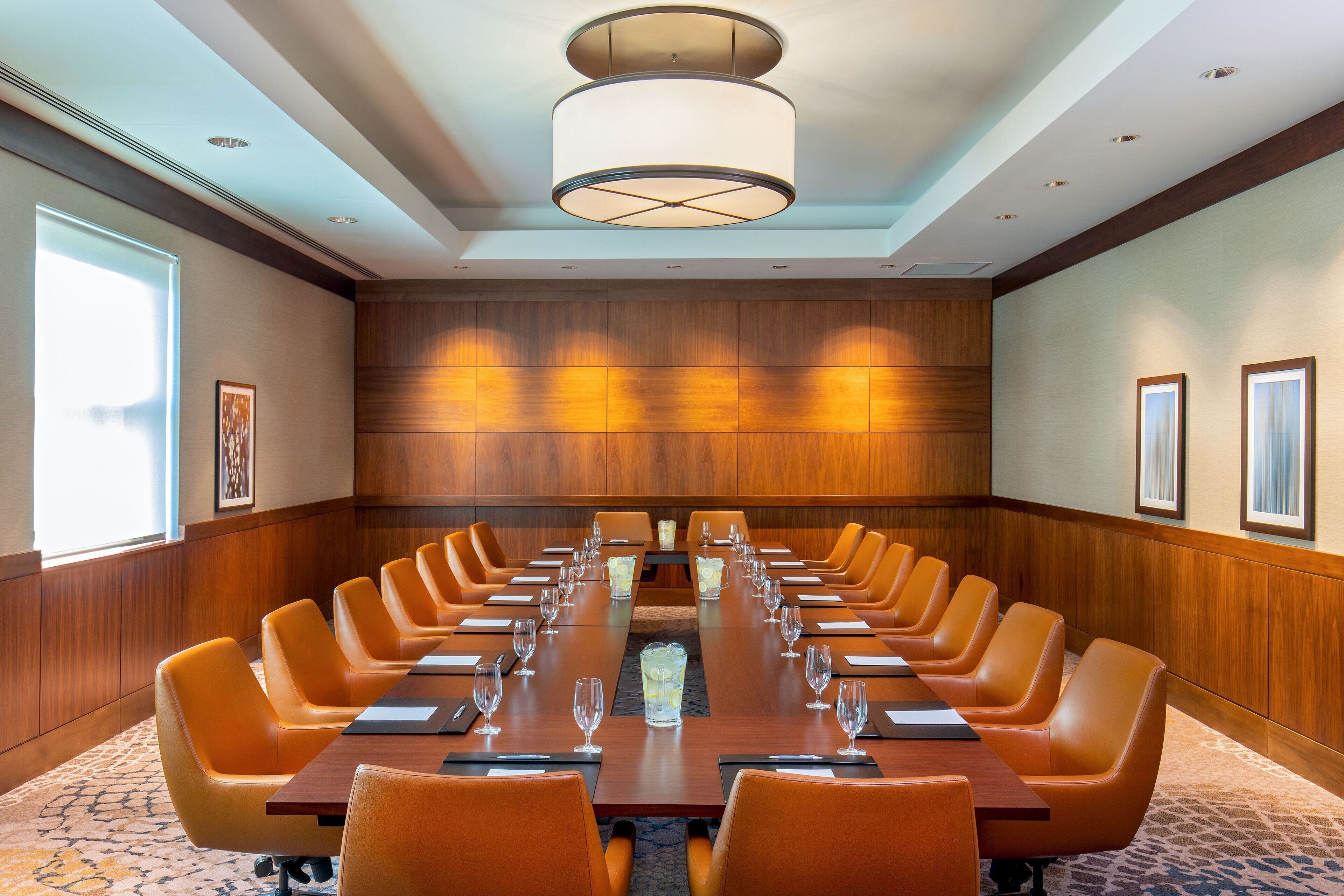 A conference room with a long table, multiple chairs, and a modern chandelier.