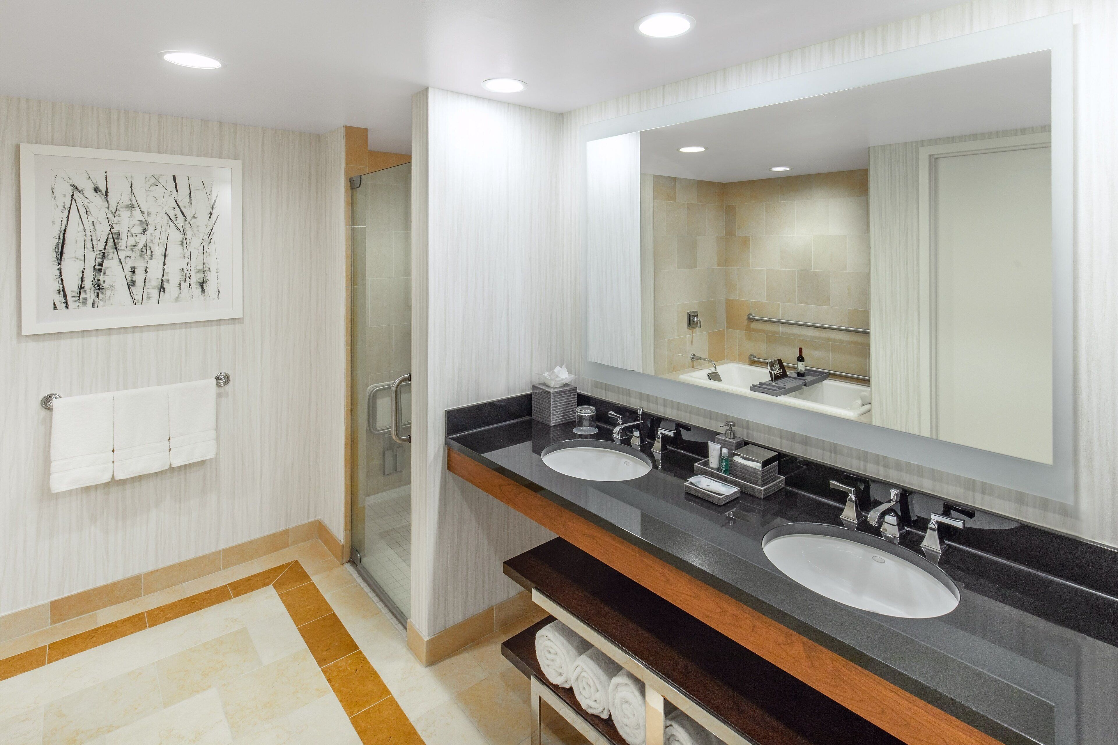 A modern bathroom with two sinks, a large mirror, and a glass shower enclosure.