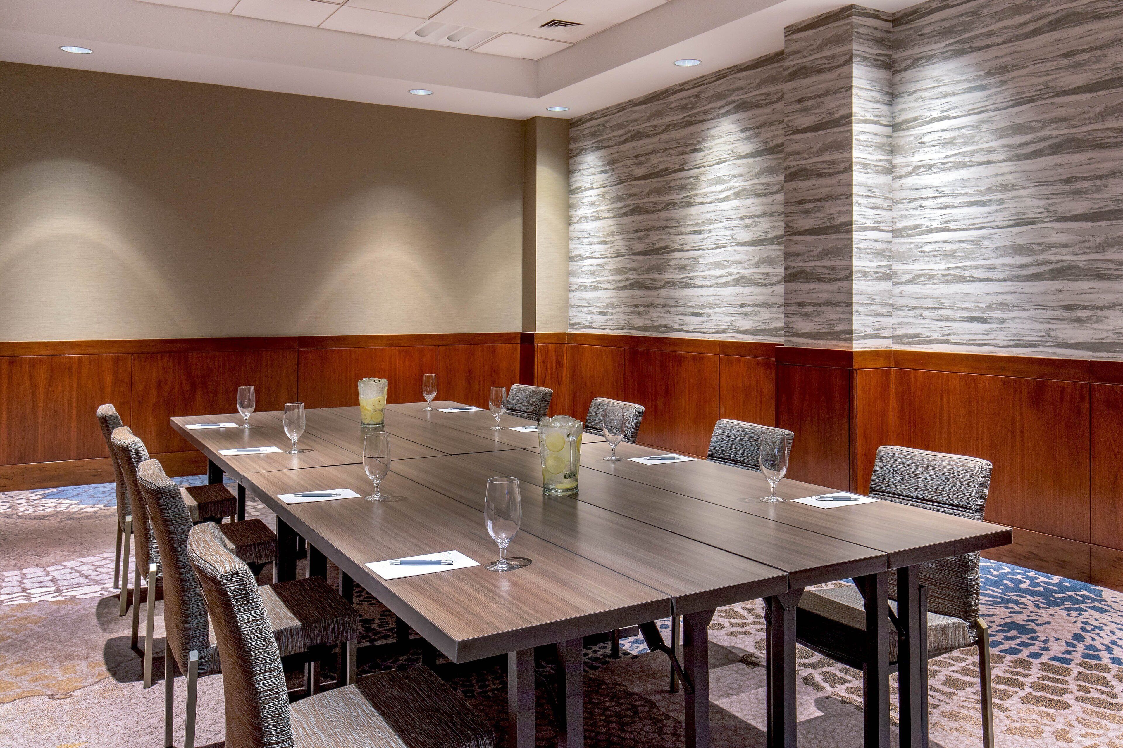 A conference room with a long table, chairs, and a patterned wall.