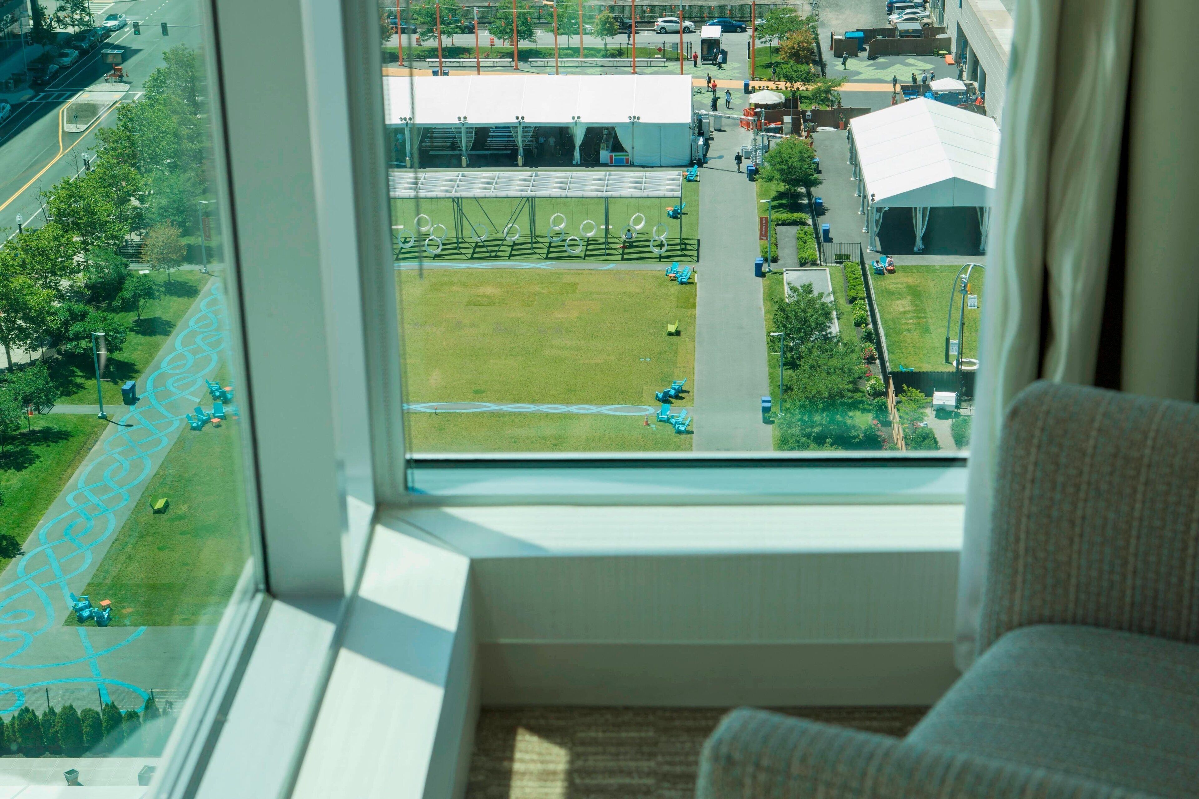 A room with a large window overlooking a sports field and a building.