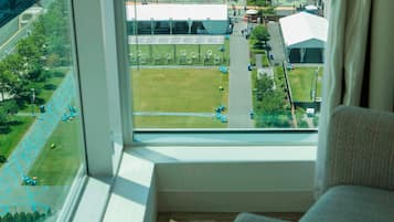 A room with a large window overlooking a sports field and a building.
