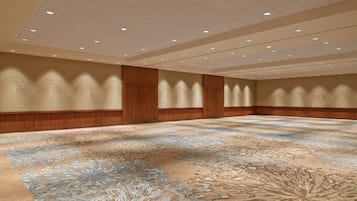 Ein großer, leerer Konferenzraum mit einem gemusterten Teppich, Holzpaneelen und eingelassener Beleuchtung.
