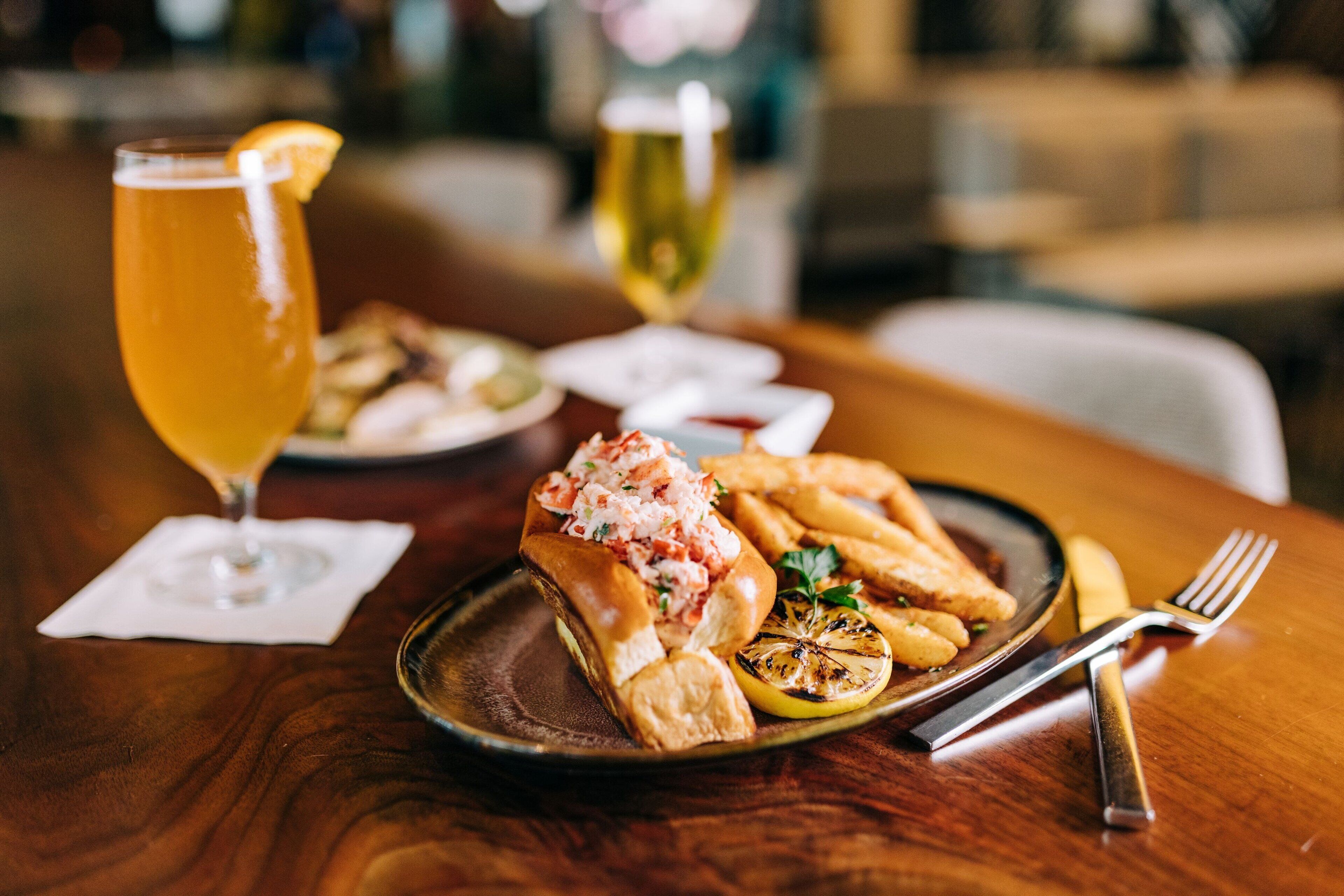 A dining table with a plate of food, a glass of beer, and a glass of wine.