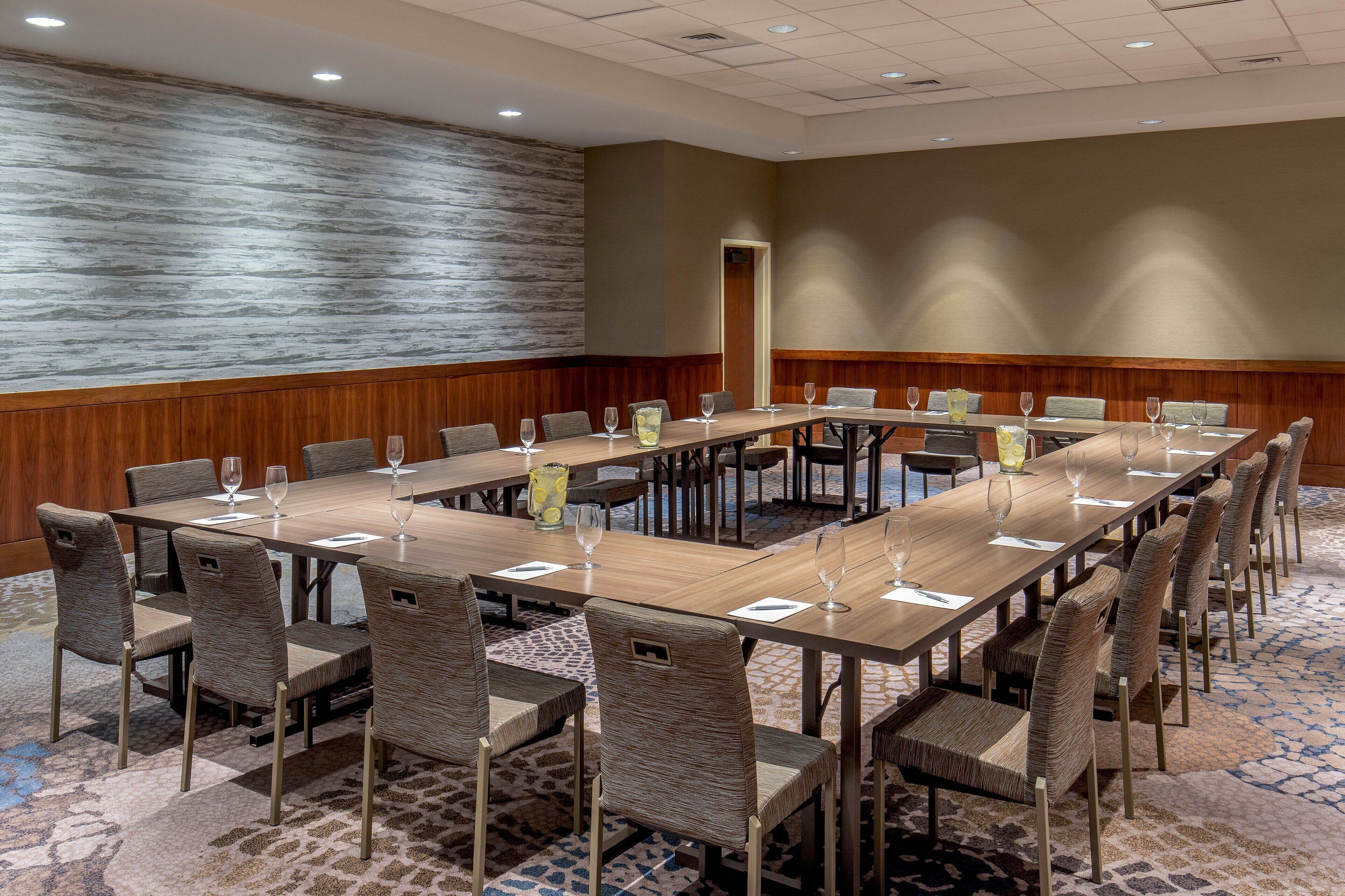 A conference room with a long table, multiple chairs, and glassware.