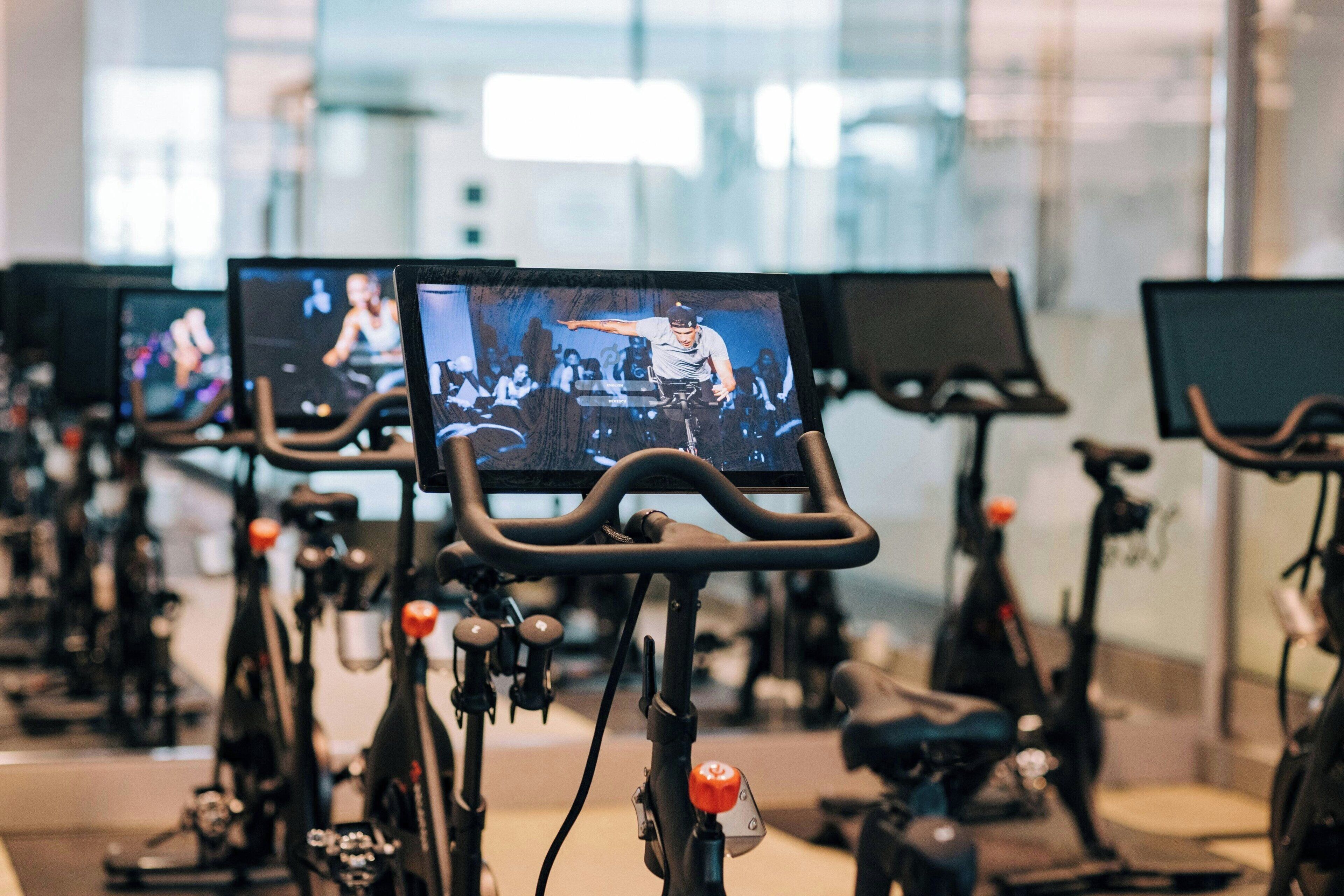A row of stationary bikes with screens displaying a person performing.