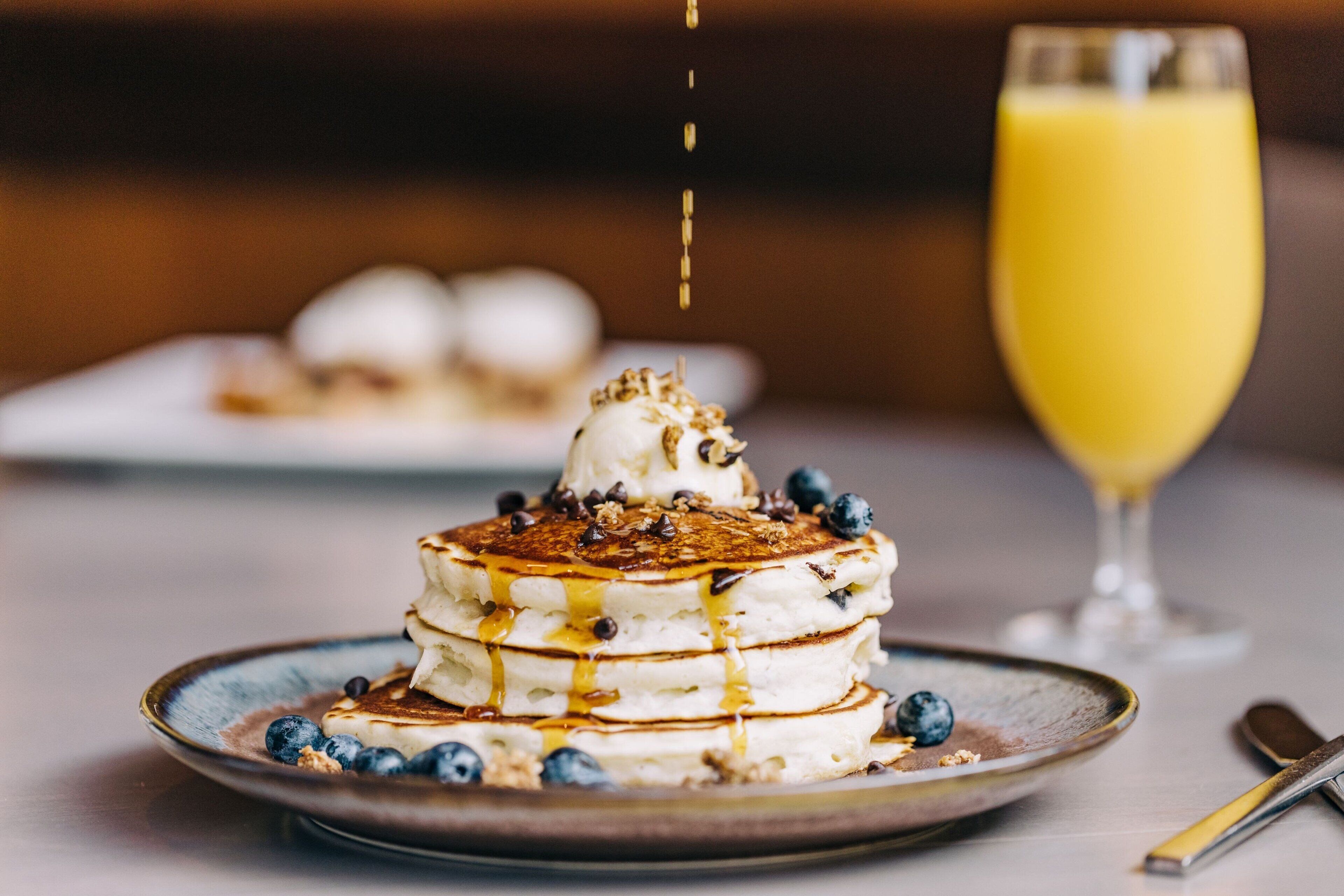 A stack of pancakes with syrup and blueberries on a plate.