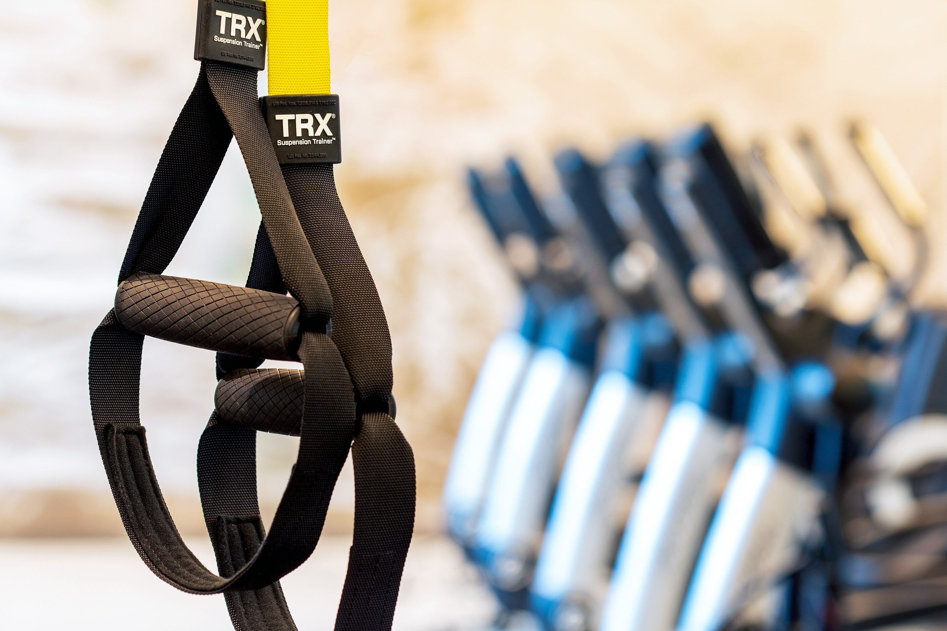 A TRX suspension trainer with a yellow handle, surrounded by other fitness equipment.