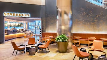 A Starbucks inside a modern building with seating areas and a large plant.