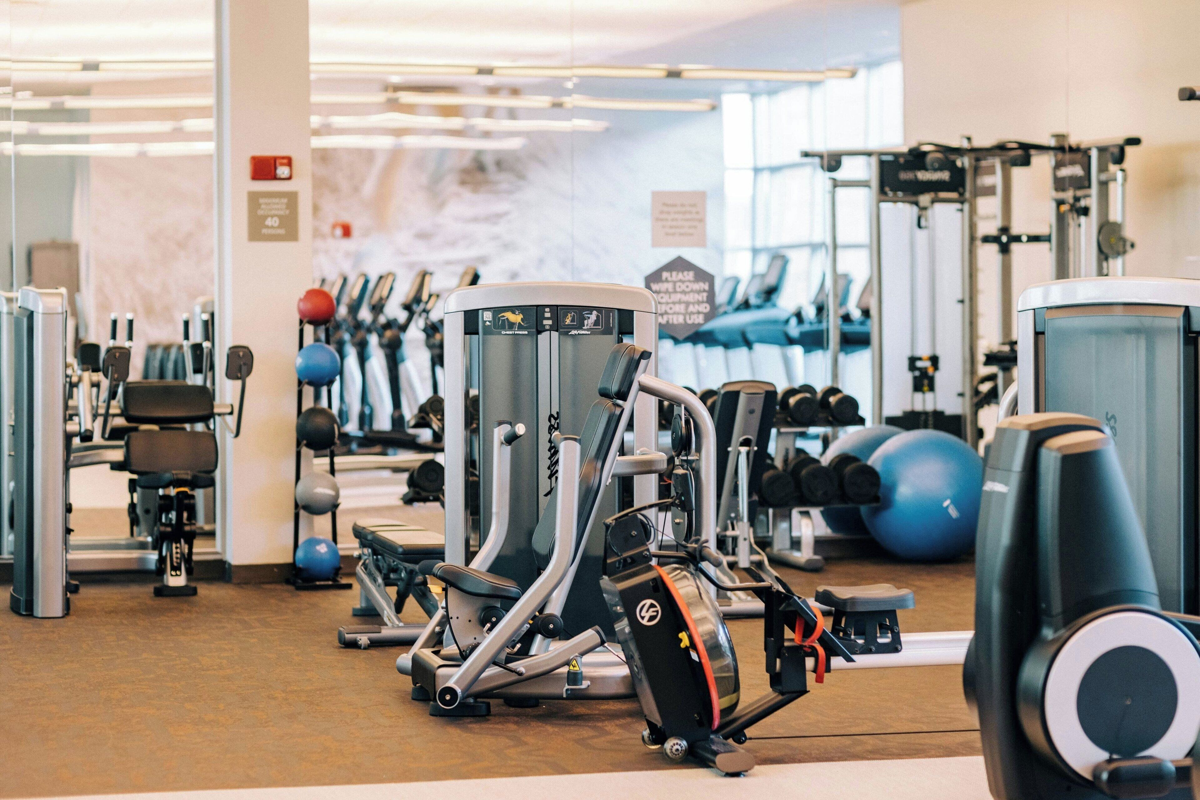 A gym with various exercise machines, free weights, and exercise balls.