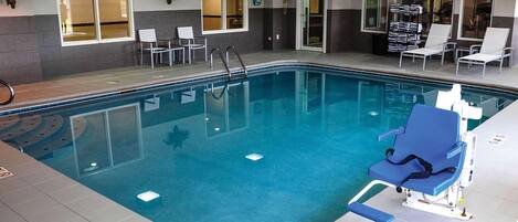 Une piscine intérieure à l’eau claire, dotée d’un poste de surveillance pour le sauveteur et de chaises longues.